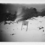Black and white photo of sign reading 'shelter' in a snowy field