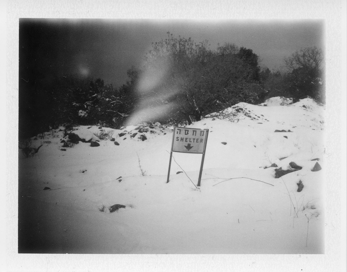 Black and white photo of sign reading 'shelter' in a snowy field