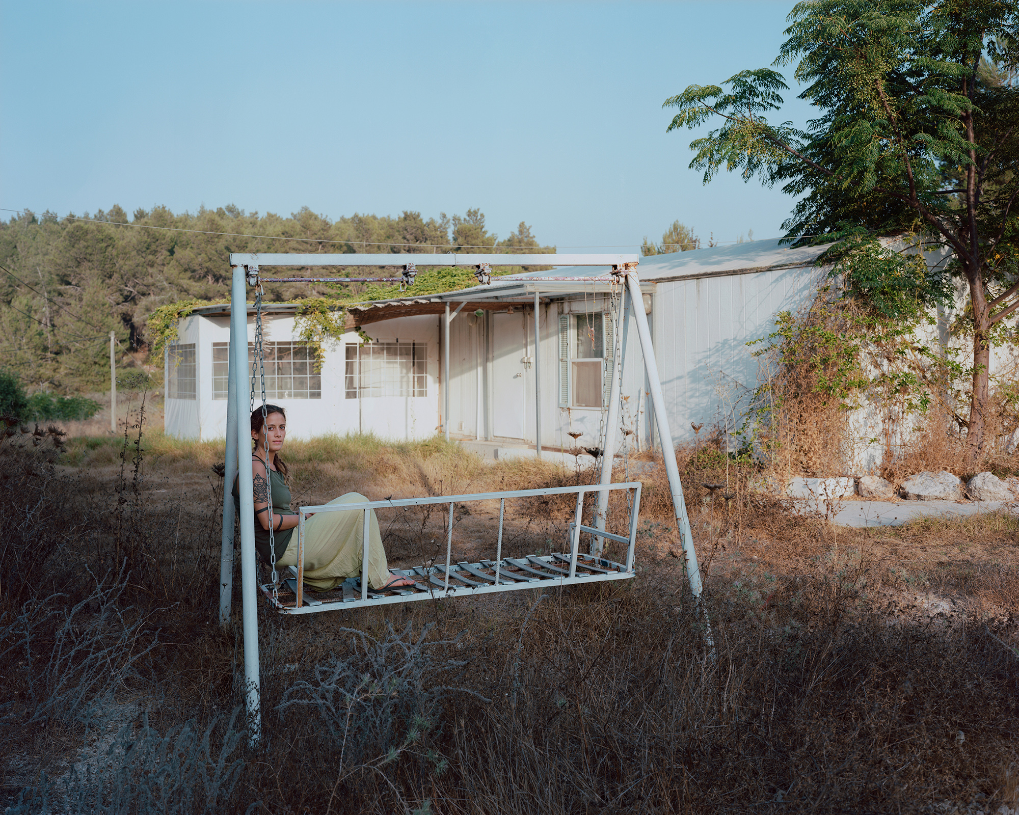 Portrait of a woman sitting on abandoned swing by Nadine Nashef