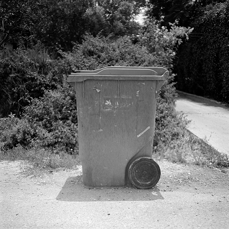 Black and white square photo of trashcan