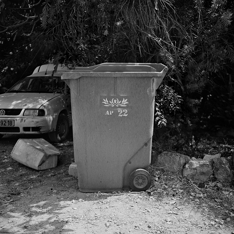 Black and white square photo of trashcan