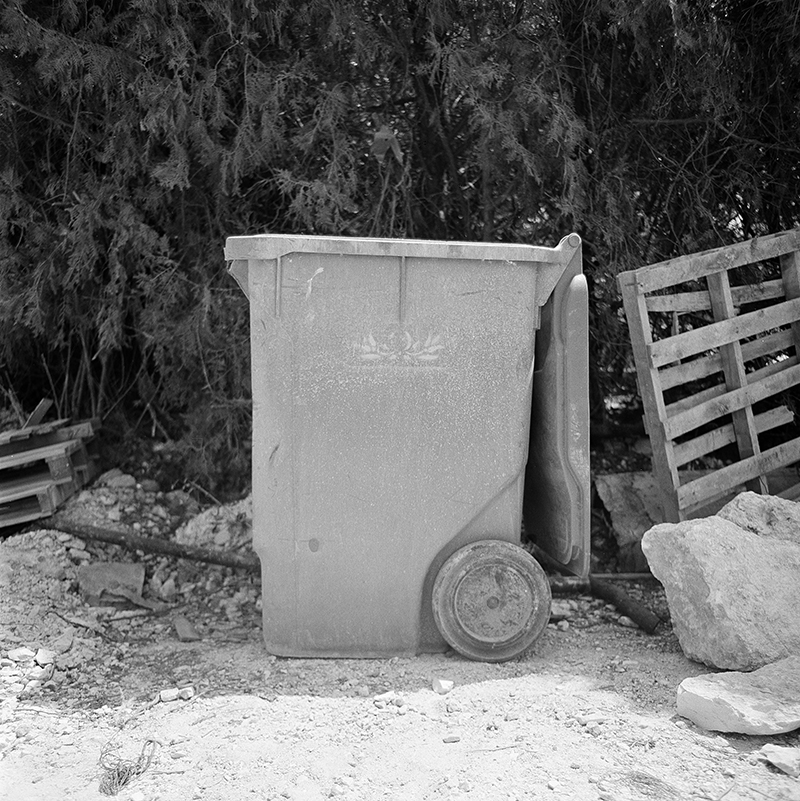 Black and white square photo of trashcan