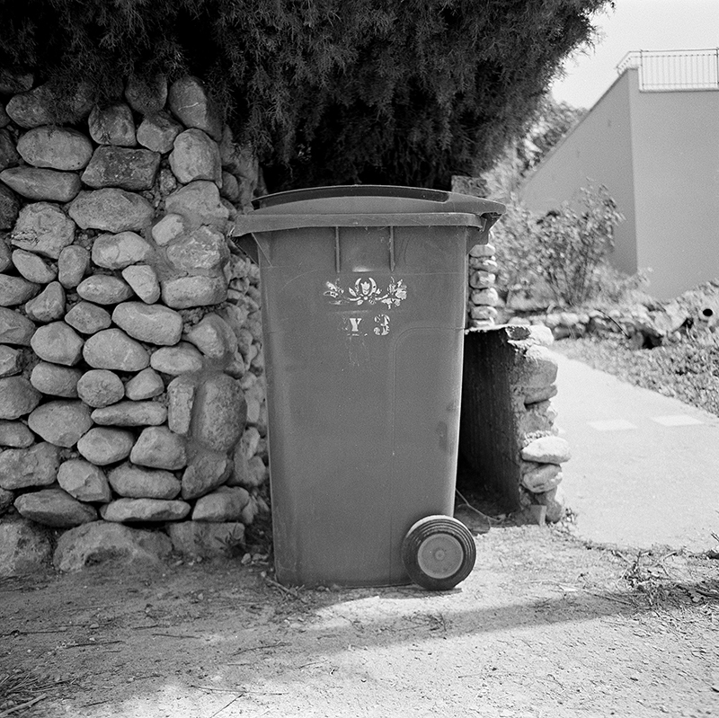 Black and white square photo of trashcan