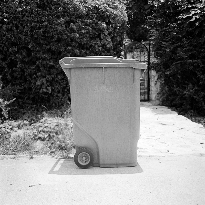 Black and white square photo of trashcan