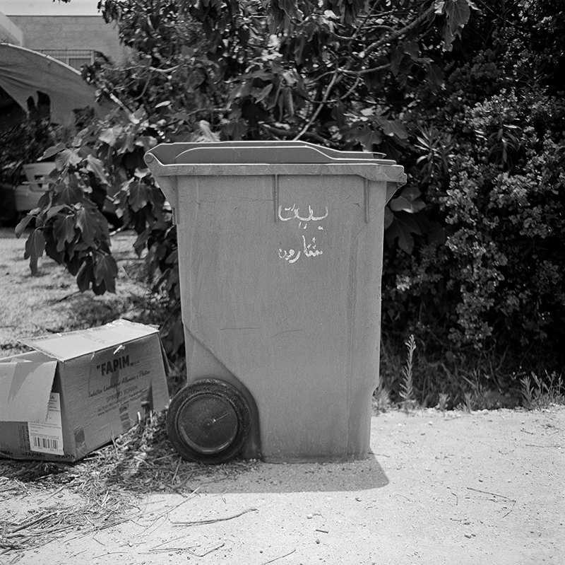 Black and white square photo of trashcan