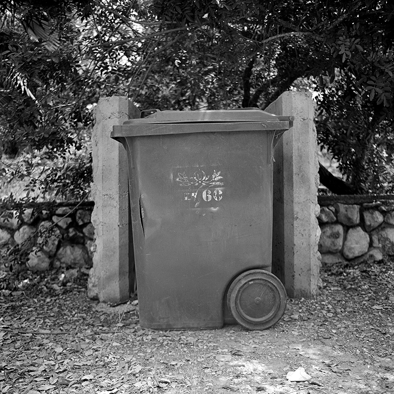 Black and white square photo of trashcan