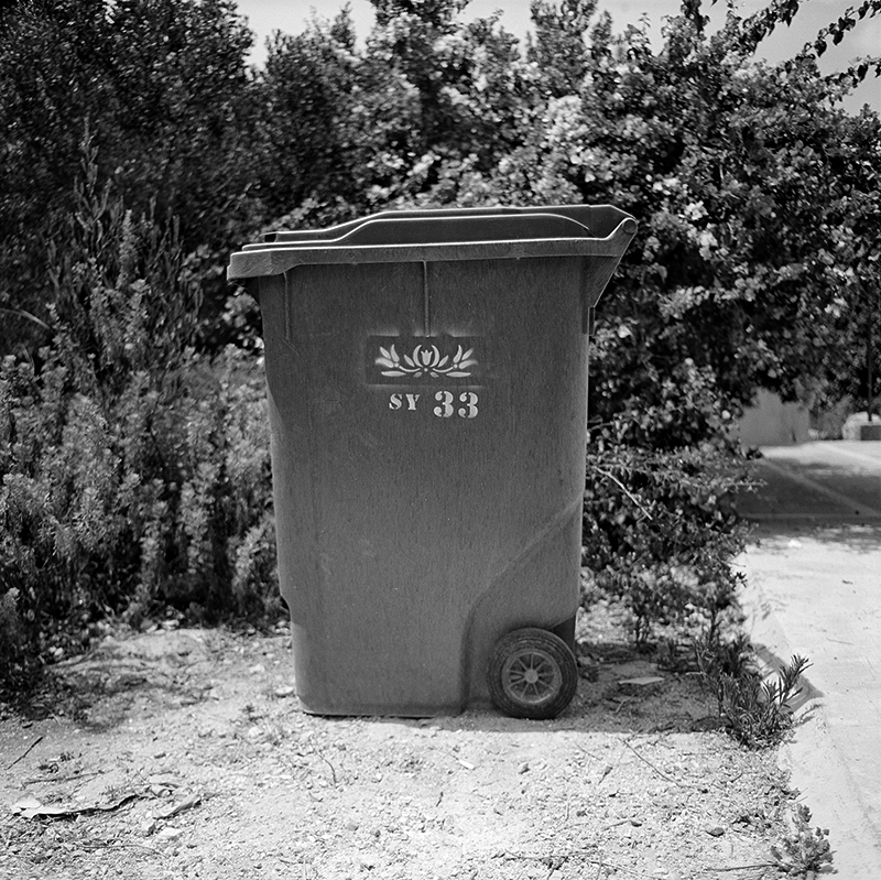 Black and white square photo of trashcan