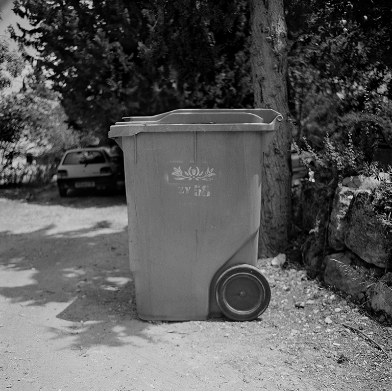 Black and white square photo of trashcan