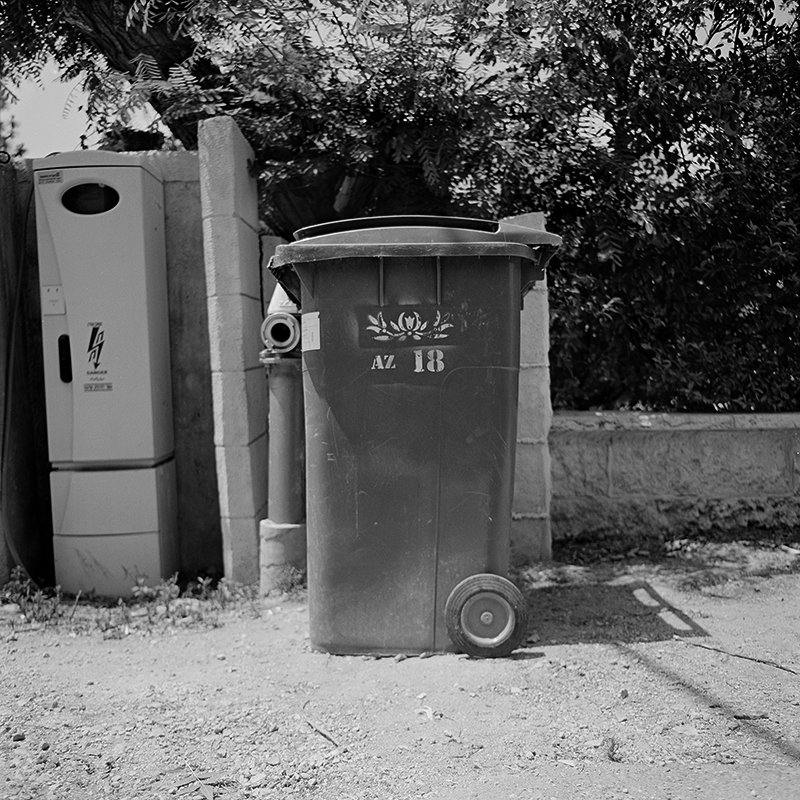 Black and white square photo of trashcan