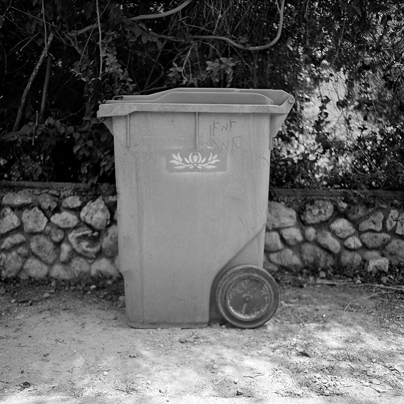 Black and white square photo of trashcan