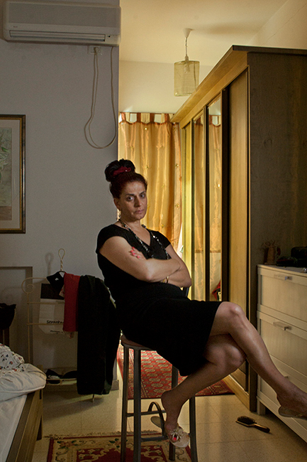 Woman sitting on high chair in the middle of bedroom.