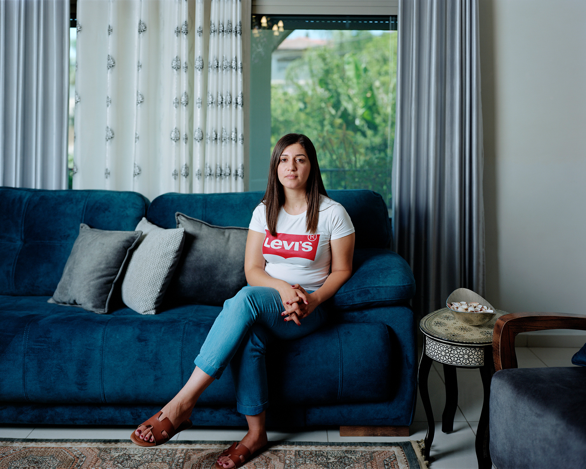 Portrait of young woman on blue sofa in her home