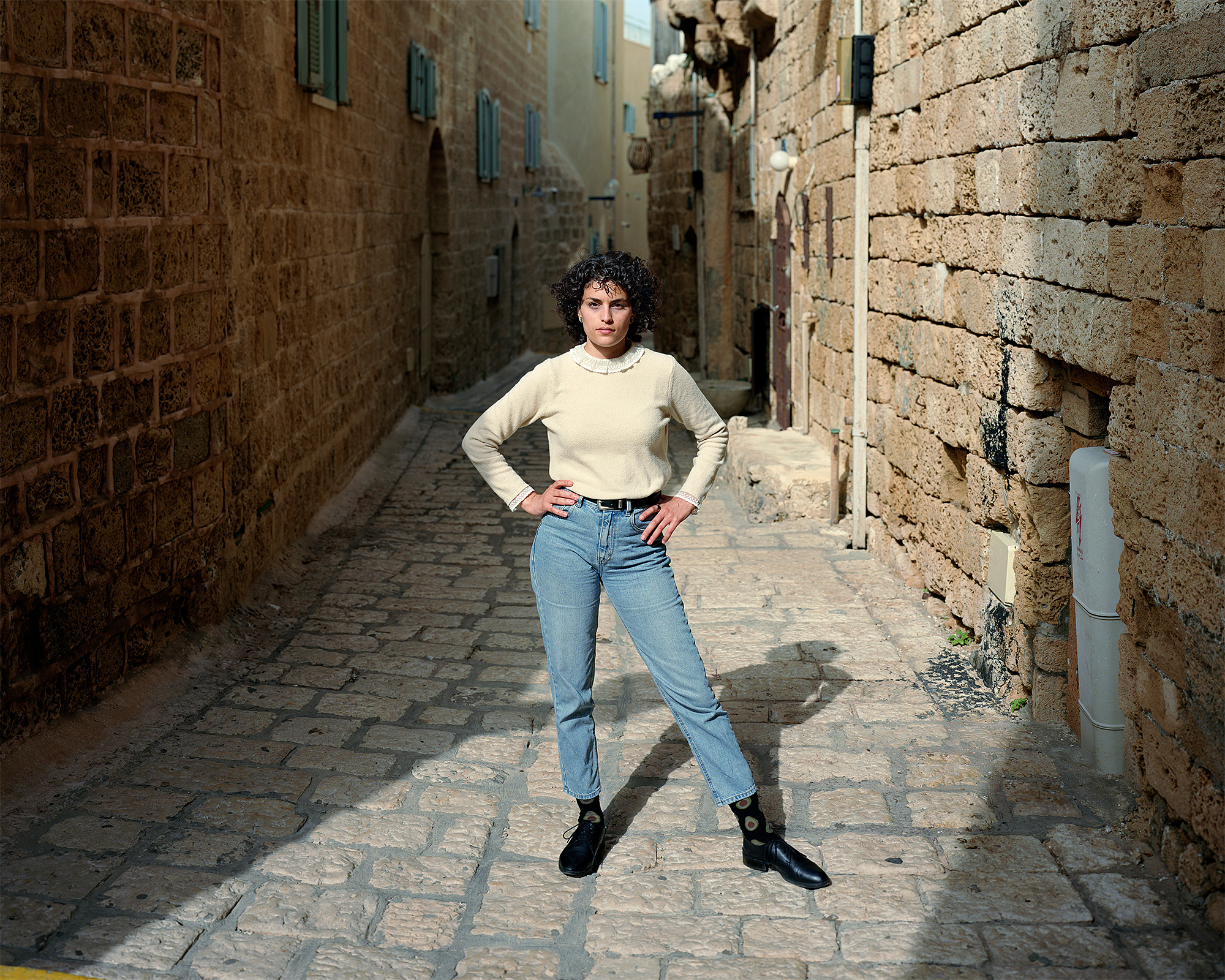 Portrait of young woman standing in alley in old city of Yaffa