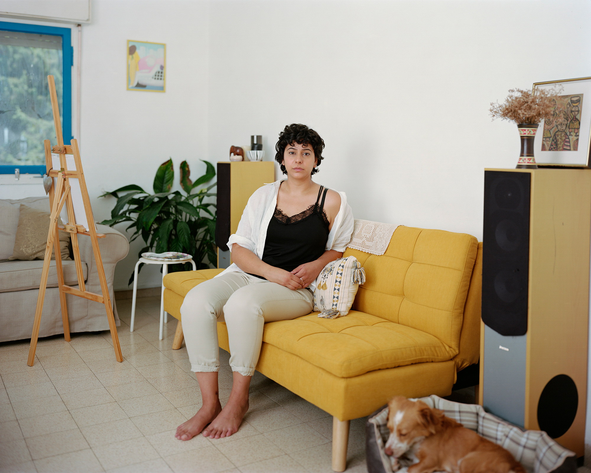 Young woman sitting on yellow sofa at home