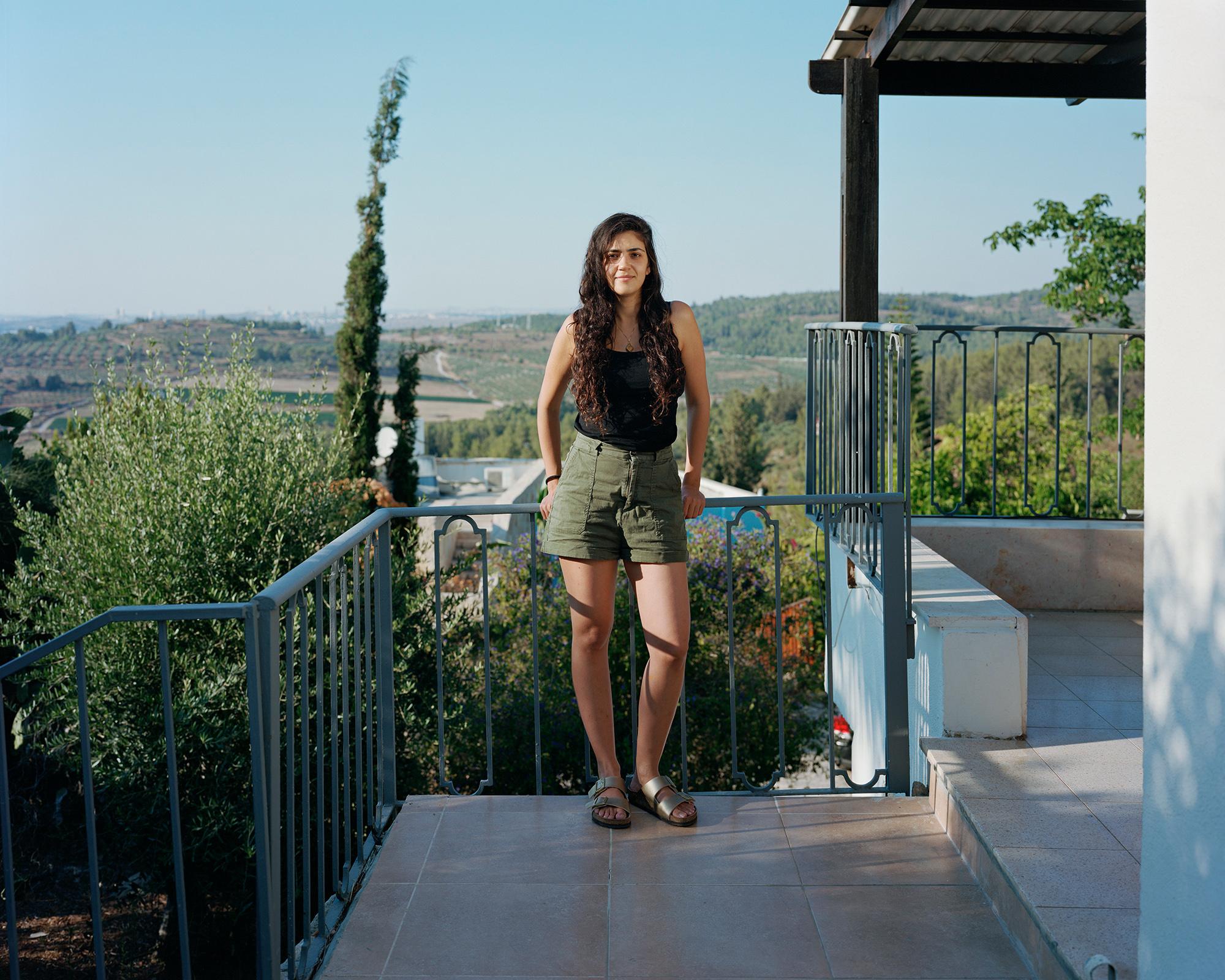 Young woman standing against balcony rails outside