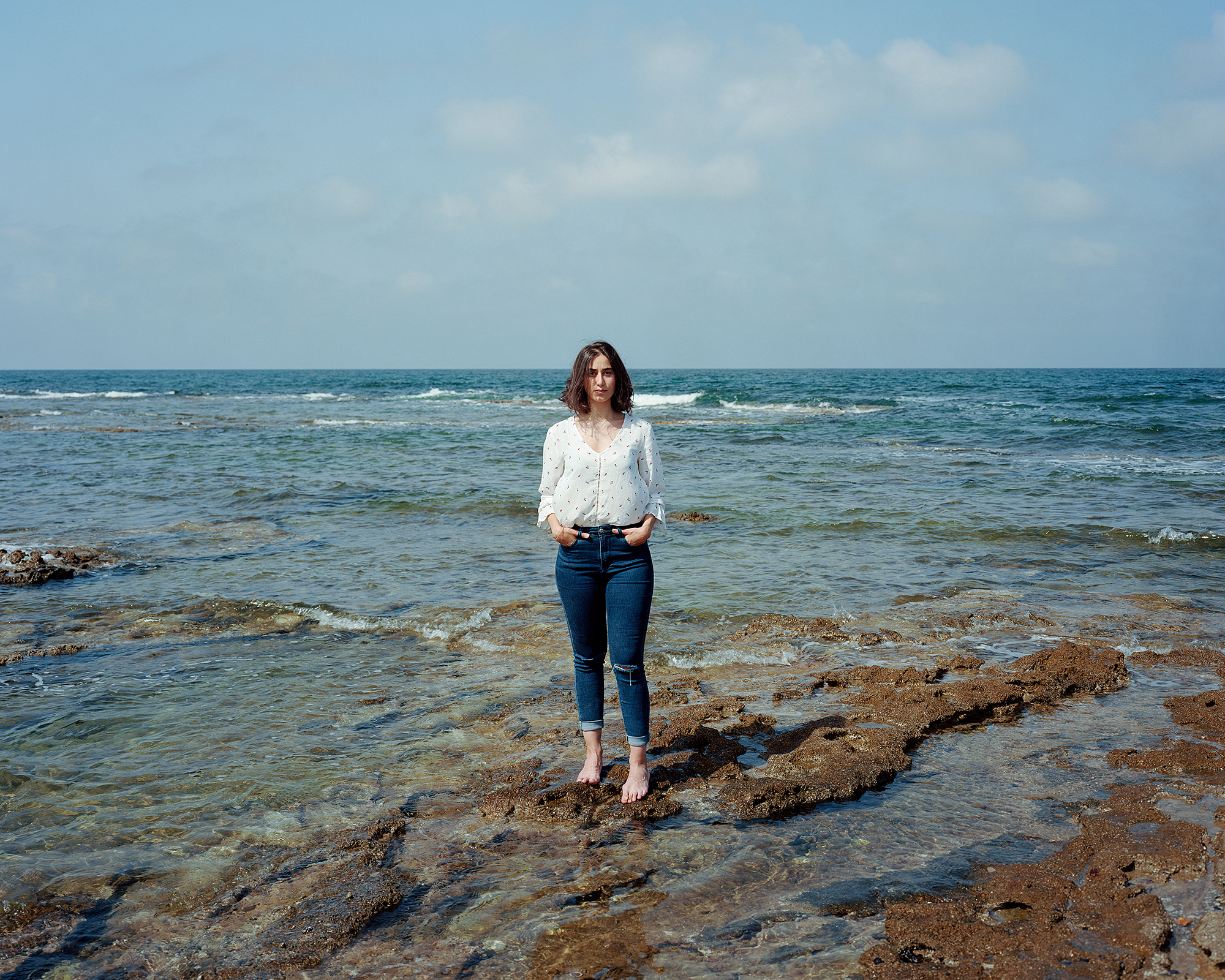 Young woman standing on rocks in the sea