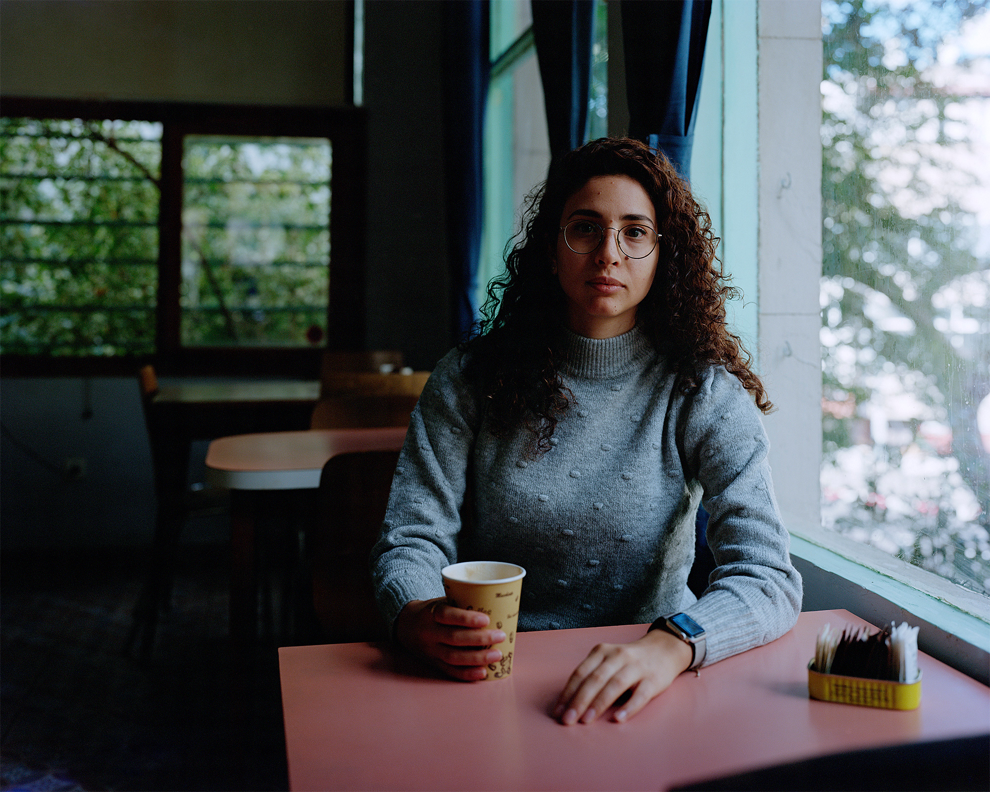 Young woman sitting next to a pink table in a cafe