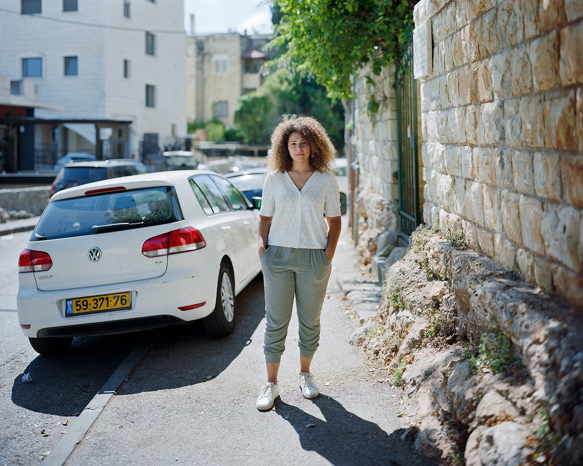 Young woman standing on sidewalk backlit by the sun