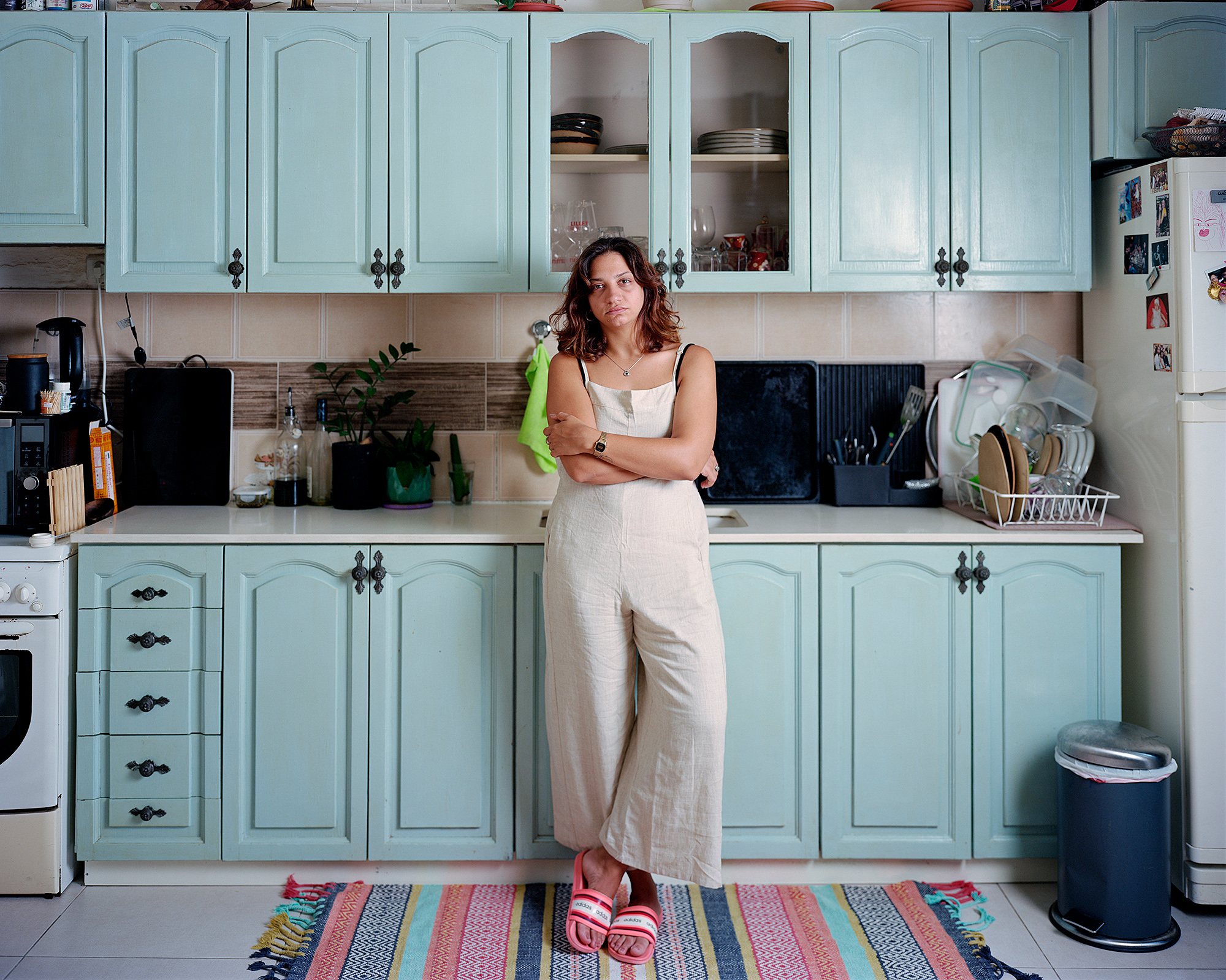 Young woman leaning against turquoise kitchen cabinets