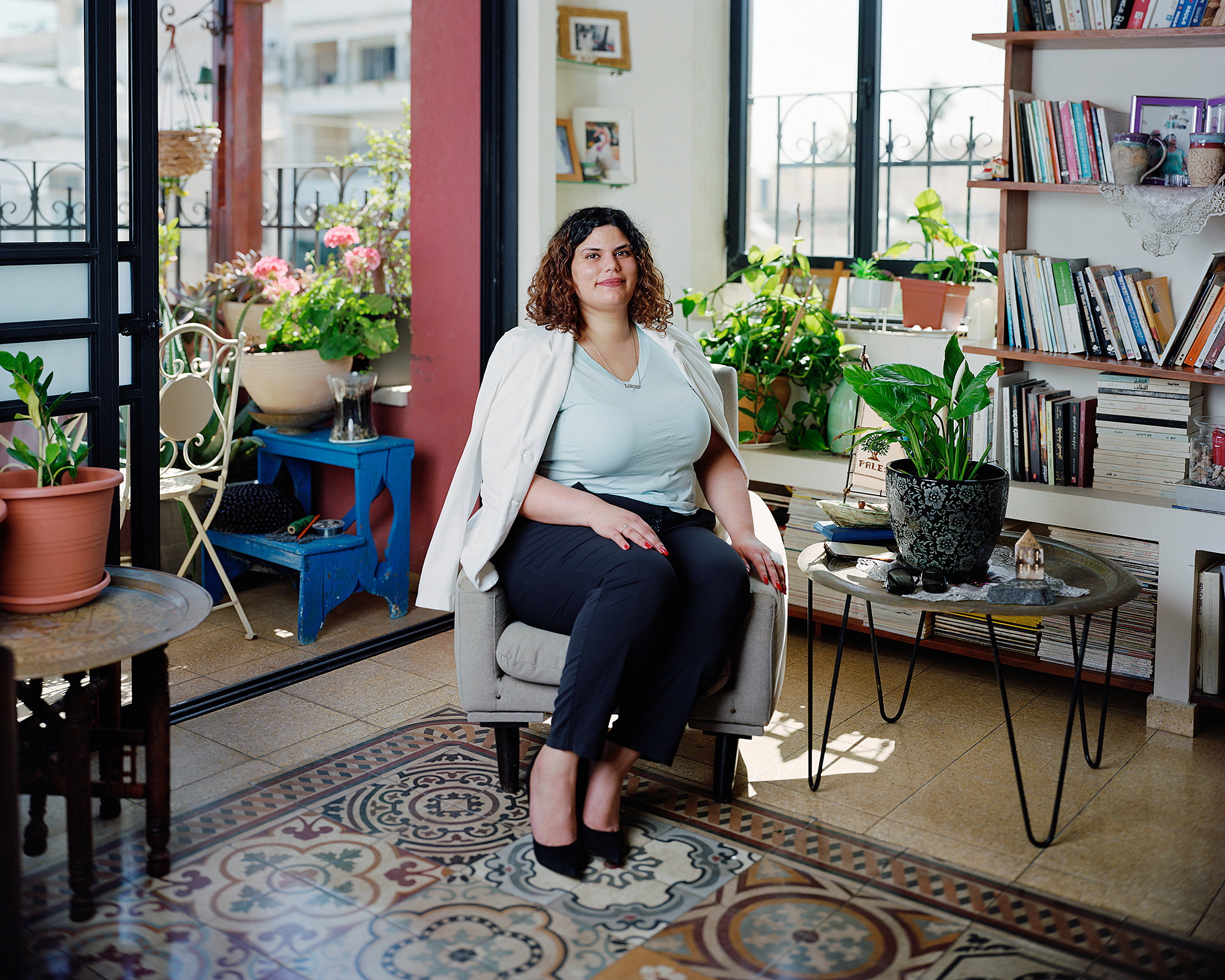 Young woman sitting on armchair in living room with pattern colored floors